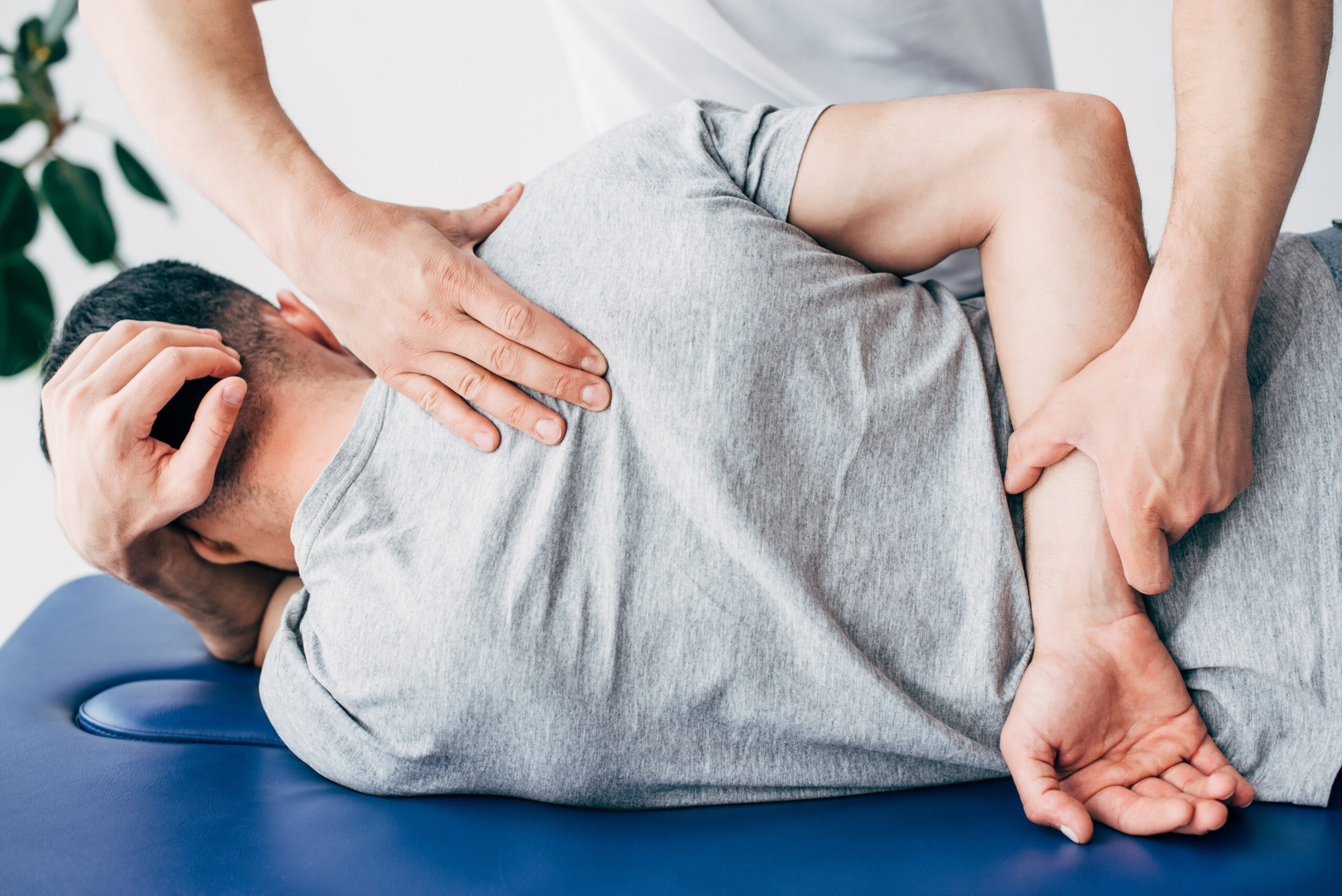 Back view of chiropractor massaging back of man lying on Massage Table in hospital