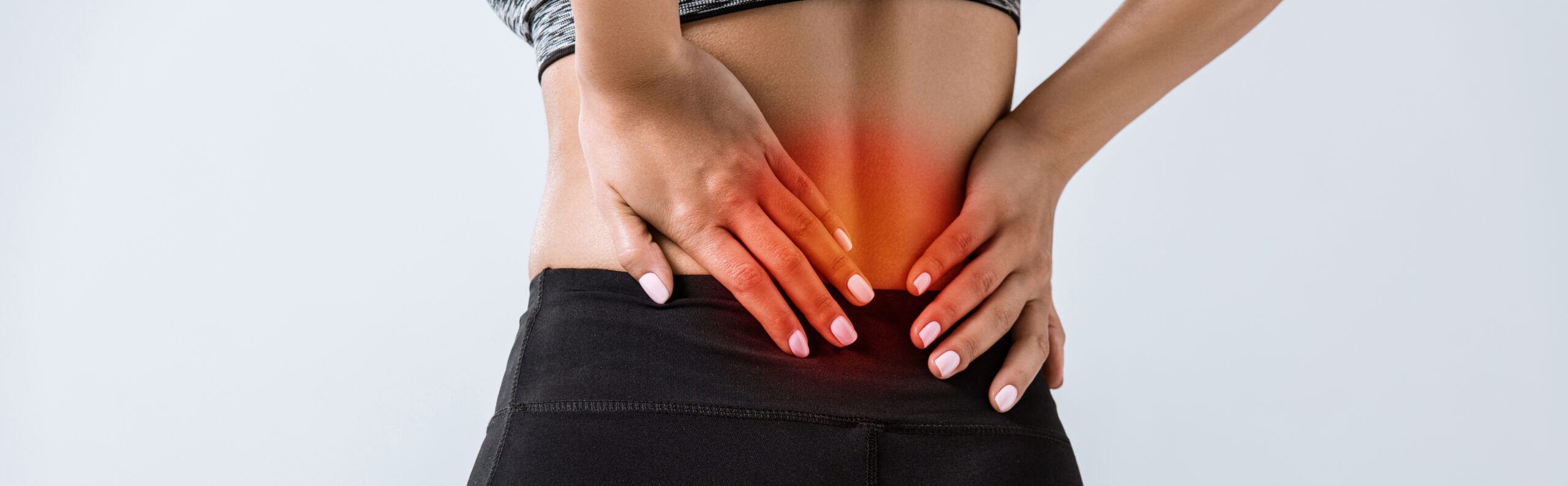 panoramic shot of sportswoman with lower back pain isolated on grey